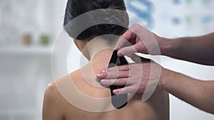 Doctor applying Y-shaped tapes on patient upper back, alternative medicine