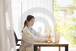 Doctor asian women sitting and working on desk using laptop and writing note at hospital,Female typing on laptop computer keyboard
