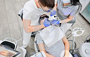 Doctor and assistant examining patient teeth with intraoral scanner.