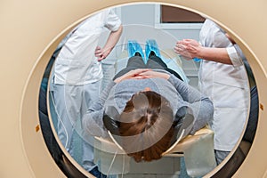 Doctor and assistant prepeared female patient for computed tomography or computed axial tomography procedure in hospital room. Sho