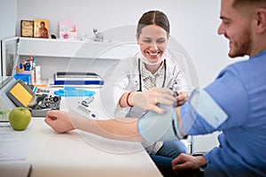 Doctor attaches cuff from blood preasure aparatus on patients arm