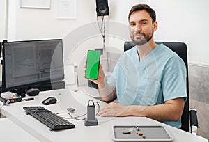 Doctor audiologist holding smartphone and hearing aids, Telemedicine concept