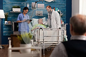Doctor auscultating chronically ill elderly woman photo