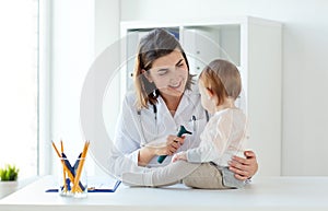 Doctor with baby and otoscope at clinic