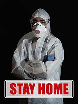 A doctor in a bacteriological protection suit, a respirator and glasses. Concept stay at home. Low key