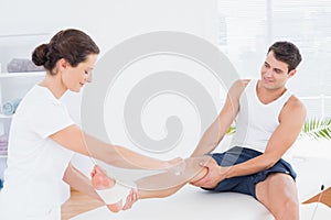 Doctor bandaging her patient ankle