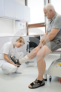 Doctor bandaging old mans injured leg