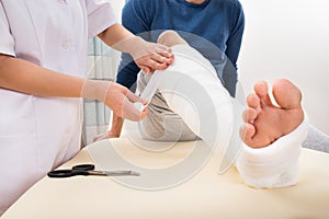 Doctor bandaging patient's leg