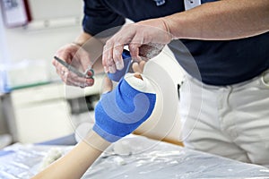 Doctor bandaging plaster cast to kids broken hand bone in hospital