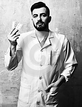 Doctor with beard and serious face expression holds pills