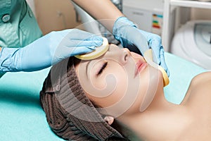 Doctor beautician cleanses skin woman with sponge. cosmetology treatment skincare face. Spa procedures