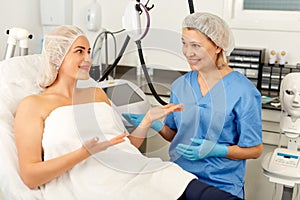 Doctor beautician discussing with woman cosmetological procedure in clinic