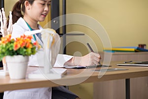 Doctor beautiful asian woman sitting and working on desk using labtop and writing note at hospital,Close up