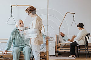 Doctor in a beige uniform talks to an elderly patient during a walk around hospital