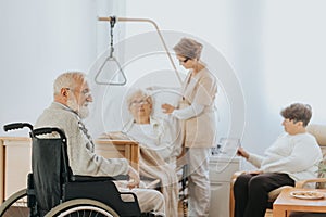 Doctor in a beige uniform talks to an elderly patient during a walk around hospital