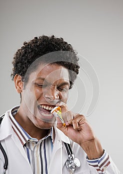 Doctor biting off lid of prescription bottle