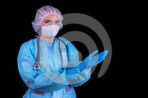 A doctor on a black background puts on medical gloves.
