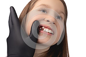 A doctor in black gloves examines the place of the child`s oral cavity in which a molar tooth was recently removed. Studio photo