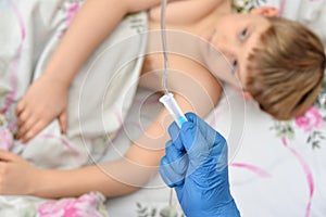 A doctor in blue gloves adjusts a dropper for a sick child