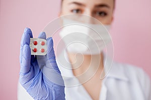 Doctor in blue gloves holds green pills in his hands on pink background. Medical industry concept