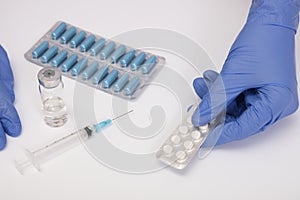 A doctor in blue nitrile gloves holding a blister of pills, capsules close up, medicament and remedy treatment concept