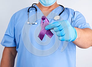 doctor in blue uniform and latex gloves holds a purple ribbon as a symbol of early research and disease control