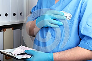 Doctor in a blue uniforme write to the blank on a background of a shelf with folders. Bribery and corruption concept photo