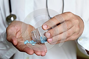 Doctor with bottle of pills, therapist giving medication in blue tablets