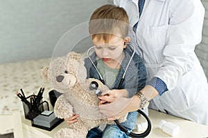 Doctor and boy patient examining teddy bear in Hospital.