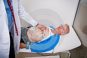 Doctor  cardiologist  is attaching vacuum sensors to an elder  senior patient for recording ECG or EKG cardiogram test