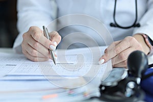 Doctor cardiologist examining patient cardiogram on paper in clinic closeup