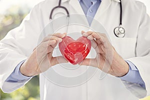 Doctor or cardiologist holding red heart background