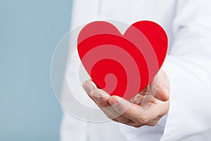 Doctor cardiologist holding a red heart in his hands. Cardiology and heart disease concept.