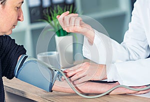 Doctor cardiologist measuring blood pressure of female patient photo