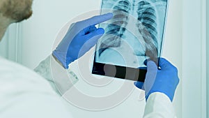 The doctor carefully examines the X-ray of the lungs of a person,diagnose a pulmonary disease,point the finger at the X-ray.