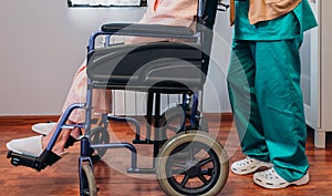 Doctor carrying elderly patient in a wheelchair