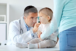 Doctor checking baby ear with otoscope at clinic