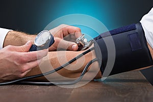 Doctor Checking Blood Pressure Of Patient At Table