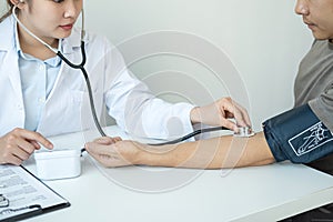 Doctor is checking blood pressure for the patient and using stethoscope to listening heartbeat