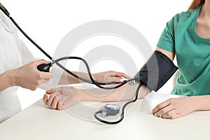 Doctor checking blood pressure of woman at table on white background, closeup