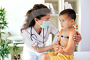 Doctor checking body temperature of young boy