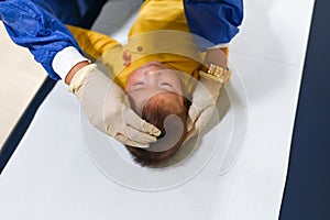 Doctor checking fontanelle of a baby boy at the routine checkup at the doctors office in the hospital