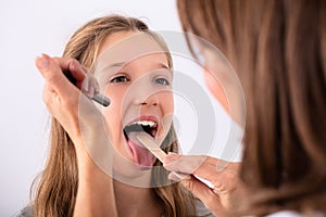 Doctor Checking Girl`s Sore Throat photo