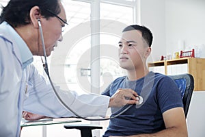 Doctor checking heartbeat of young man