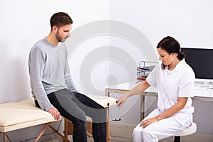 Doctor Checking Knee Reflexes Of Patient With Reflex Hammer