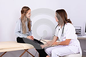 Doctor Checking Knee Reflexes Of Patient With Reflex Hammer photo