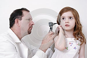 Doctor checking little girl's ear