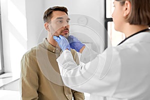 doctor checking lymph nodes of man at hospital