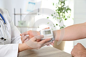 Doctor checking man`s pulse with medical device in hospital