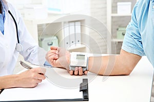 Doctor checking mature man`s pulse with medical device